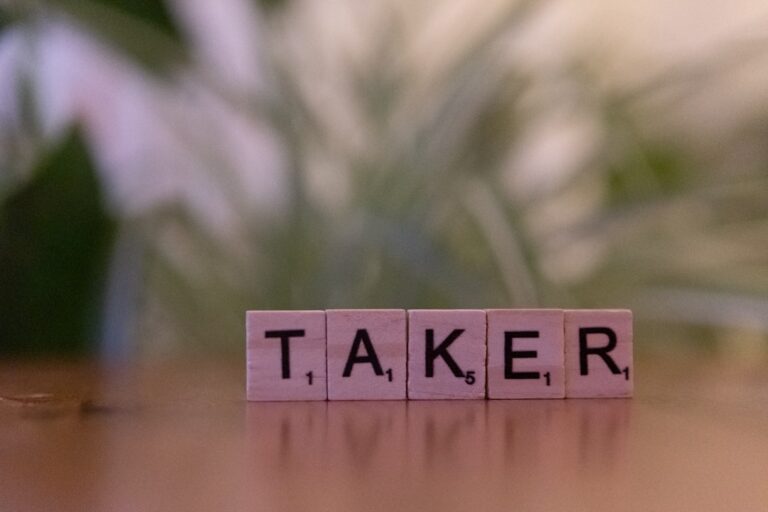The word taker spelled with scrabble blocks on a table